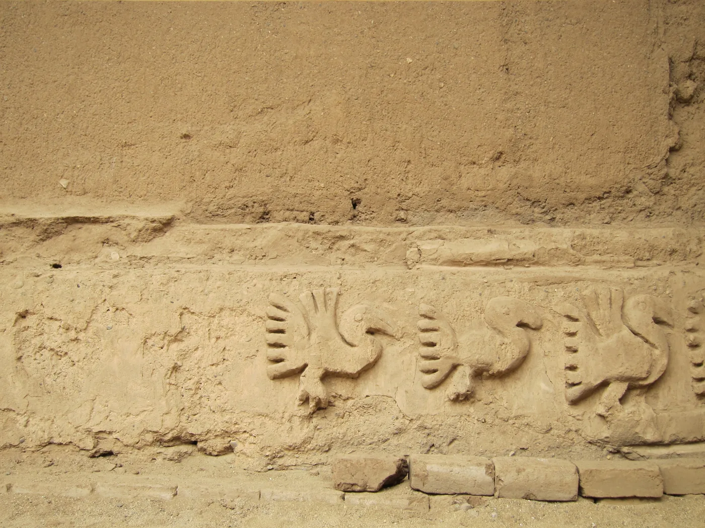 Relieve de adobe con aves marinas y patrones geométricos en Chan Chan